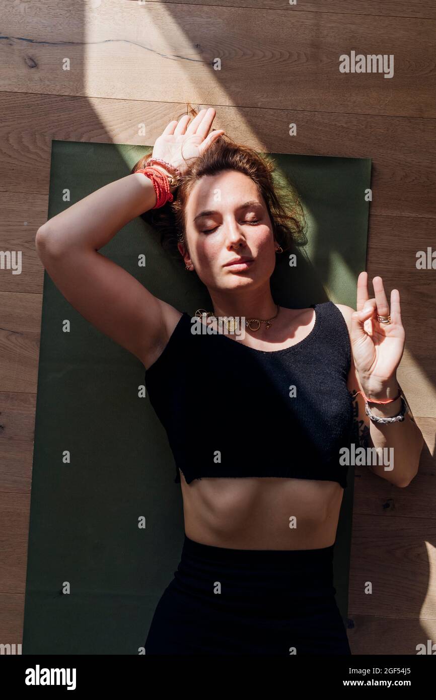 Woman practicing yoga while lying on exercise mat Stock Photo