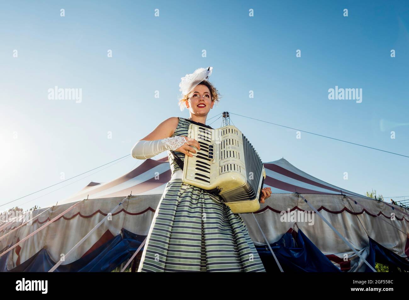 Female performer playing accordion in front of circus tent Stock Photo