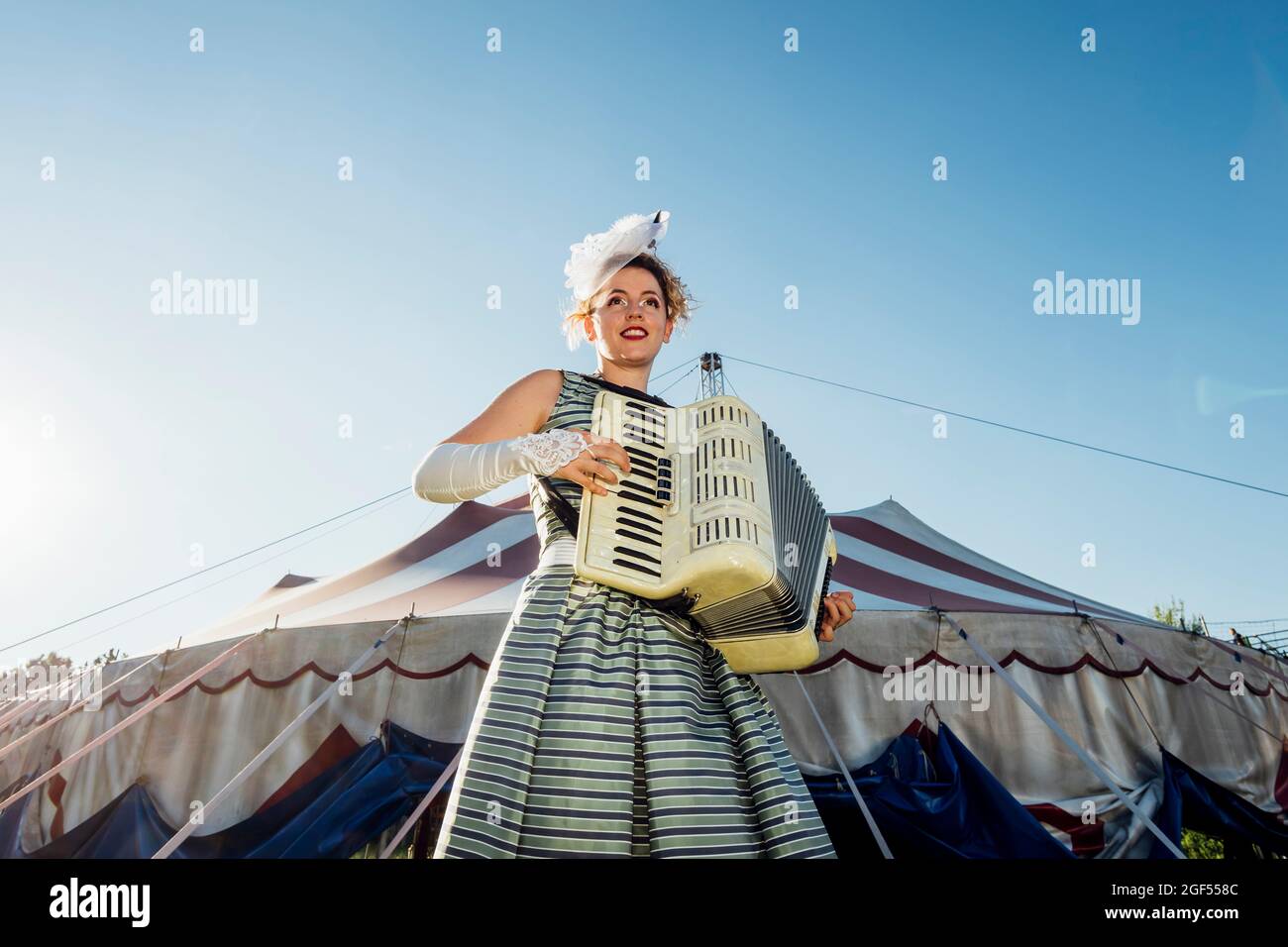 Female performer playing accordion in front of circus tent Stock