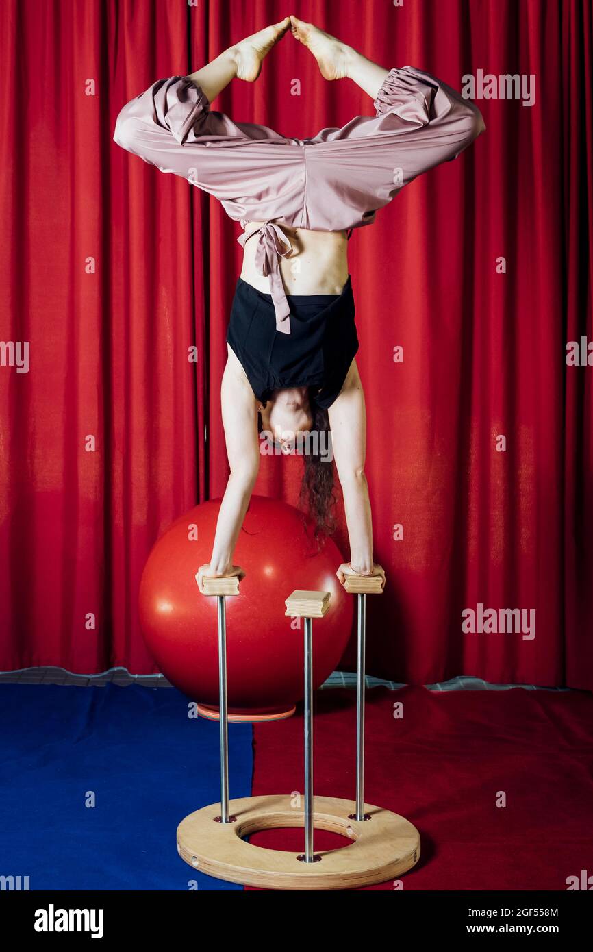 Female performer stretching legs while doing handstand at circus Stock Photo