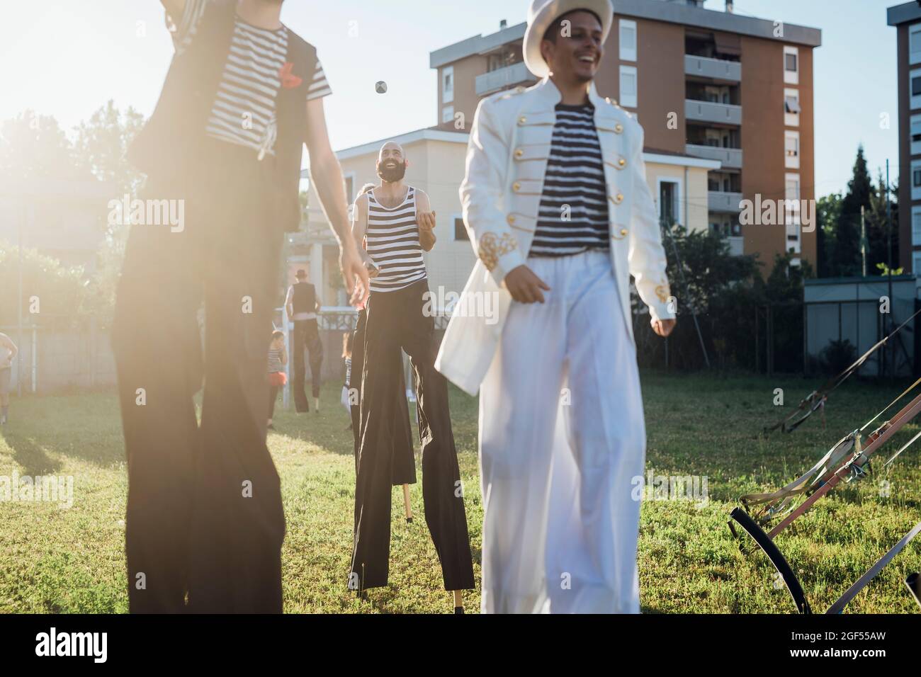 Smiling male artist walking with stilts on meadow Stock Photo