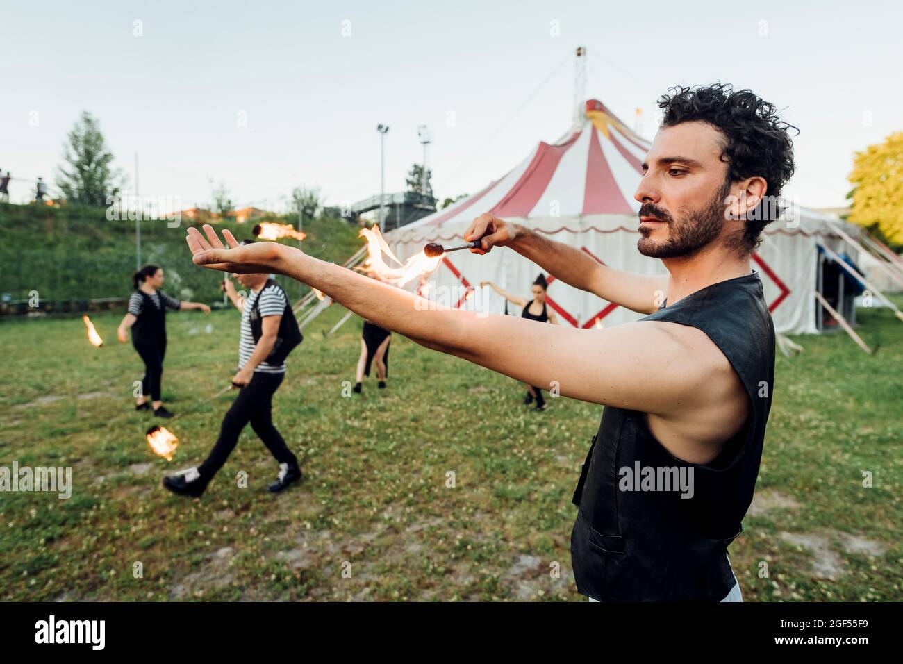 Male fire dancer doing rehearsal outside circus tent Stock Photo