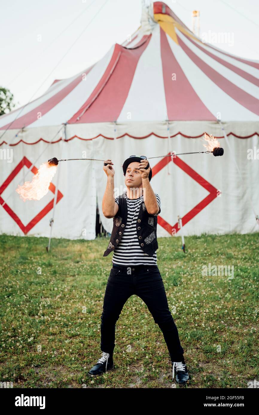 Male fire dancer practicing in front of circus tent Stock Photo