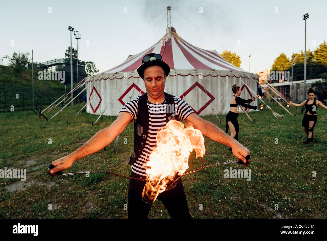 Male fire dancer holding fire equipment while practicing in front of circus tent Stock Photo