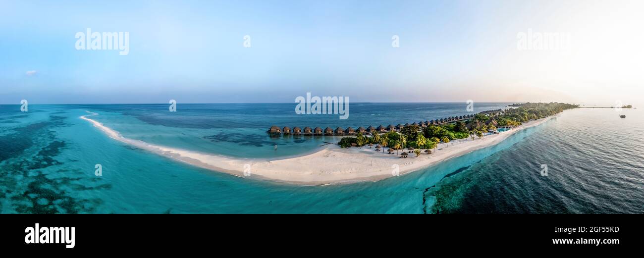 Maldives, Lhaviyani Atoll, Kuredu, Aerial panorama of coastal beach and row of resort bungalows surrounded by waters of Indian Ocean at sunrise Stock Photo