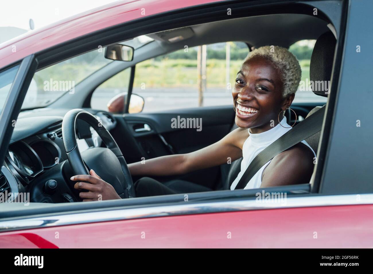 Cheerful young woman sitting in car Stock Photo