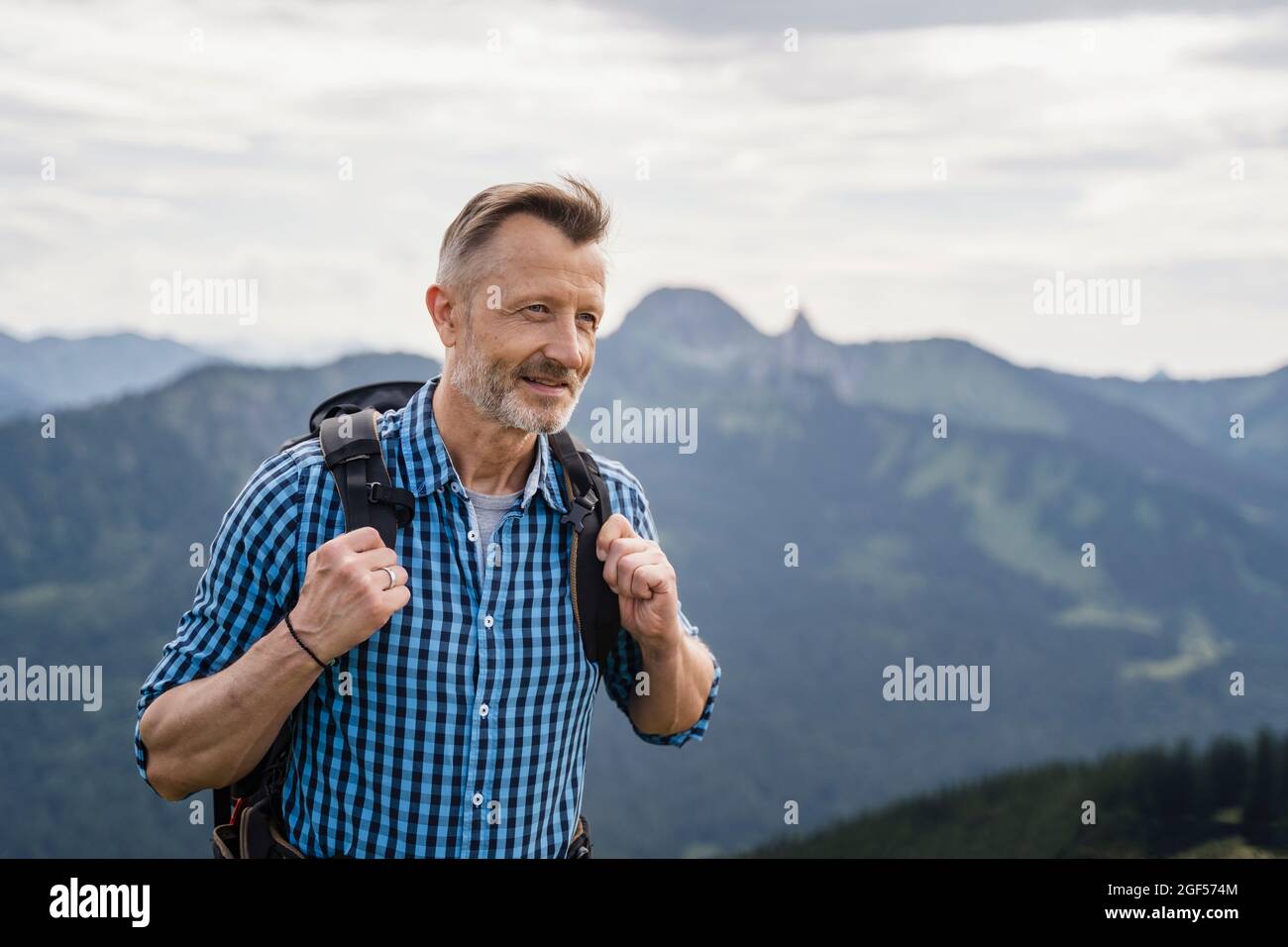 Smiling male backpacker hiking on mountain Stock Photo