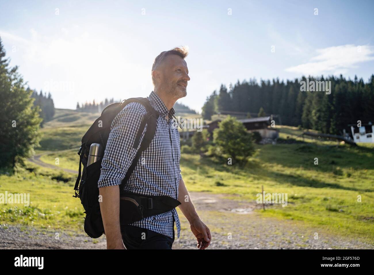 Smiling male backpacker hiking on sunny day Stock Photo