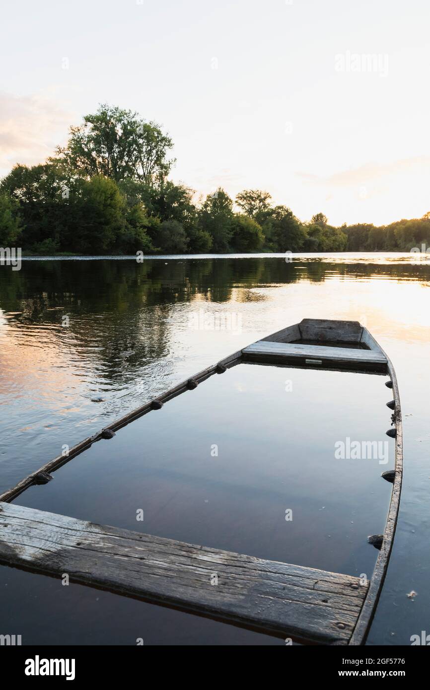 Sunken boat left at bank of Dordogne River at sunset Stock Photo