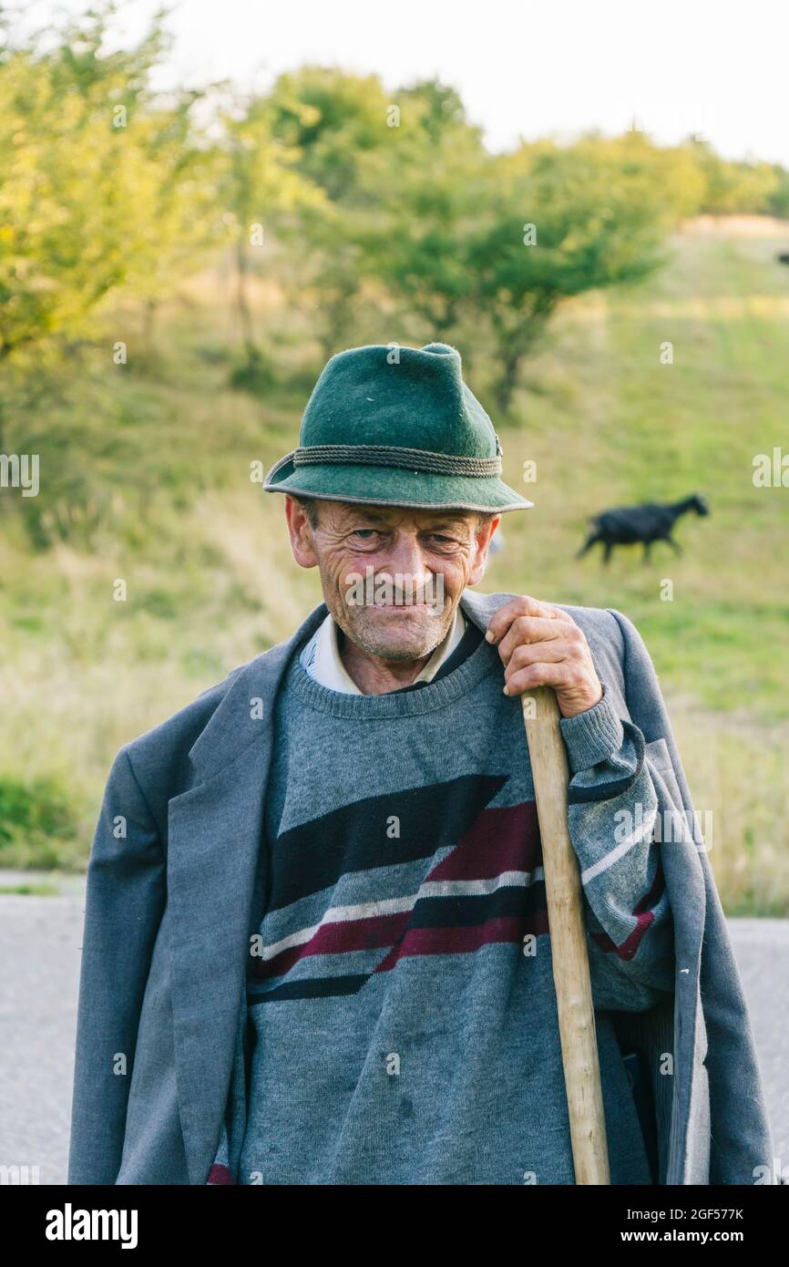 Senior male goat herder holding cane Stock Photo