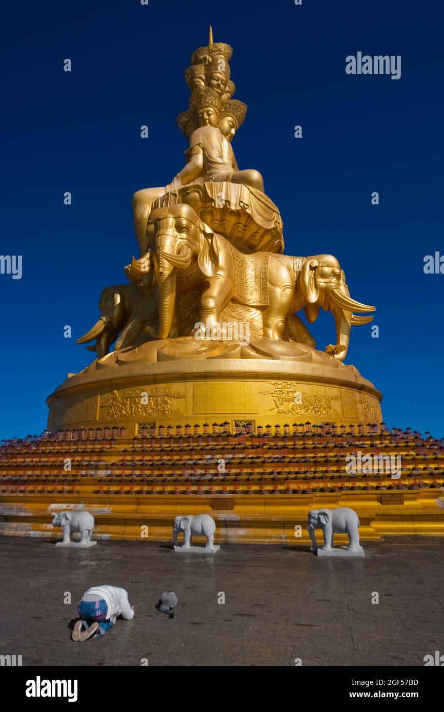 China, Sichuan, Emeishan City, Person praying in front of golden statue of Samantabhadra at summit of Mount Emei Stock Photo