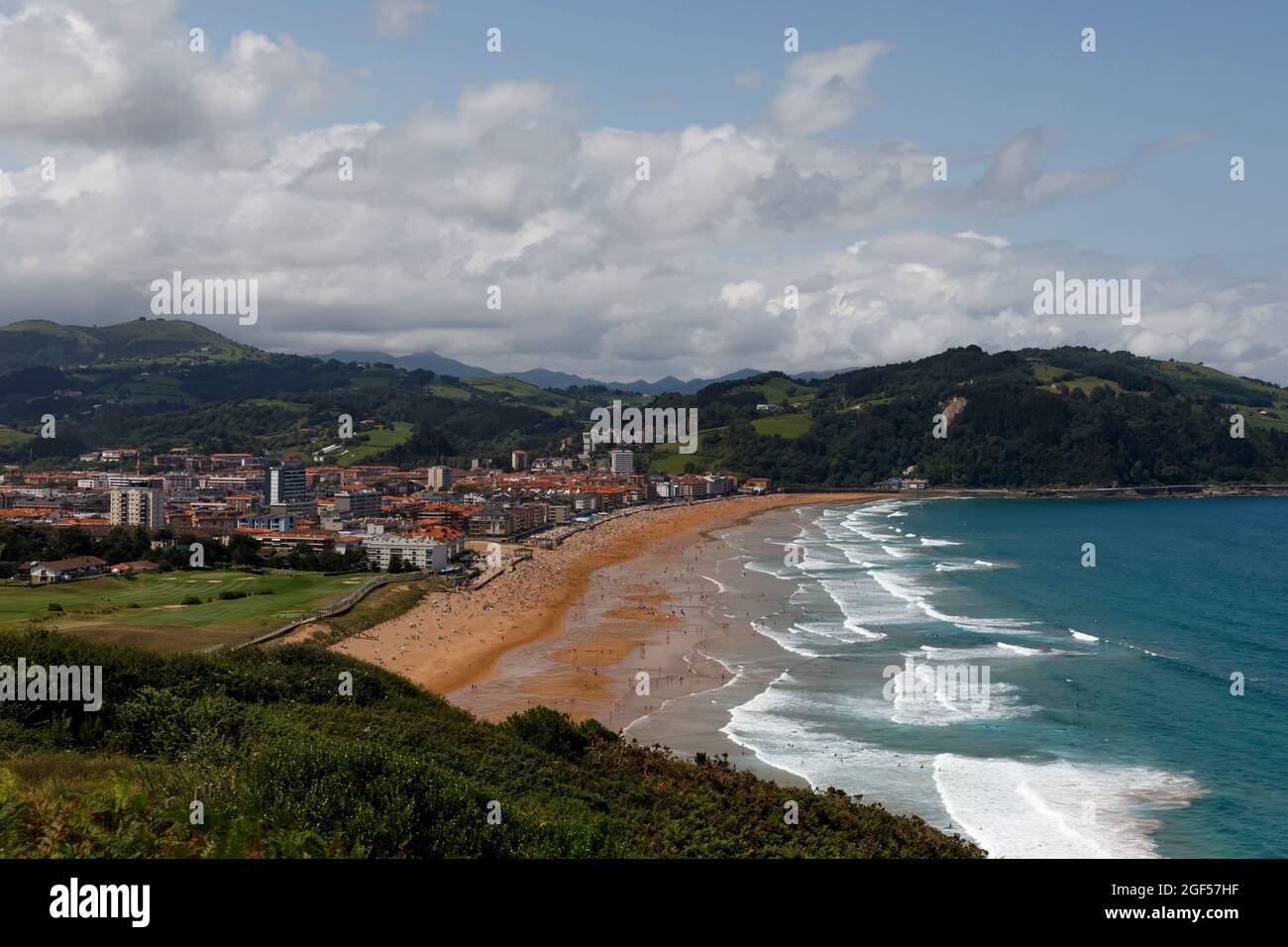 Spain, Gipuzkoa, Zarautz, Clouds over coastal town with splashing waves in foreground Stock Photo