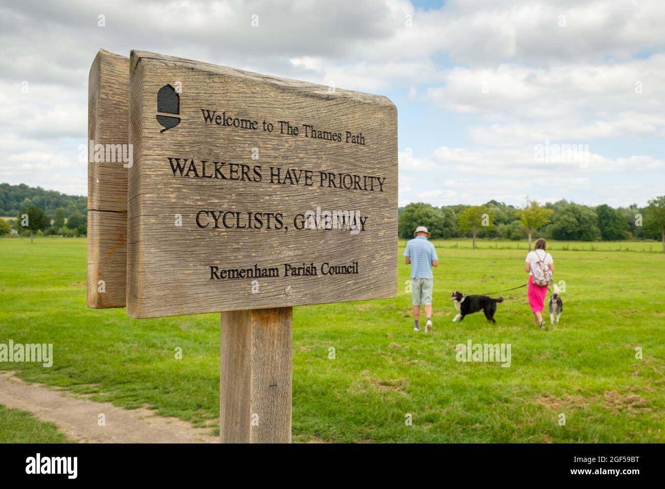 A  wooden sign on Thames Path by the towpath on the River Thames reads 'Walkers have priority, cyclists give way' Stock Photo