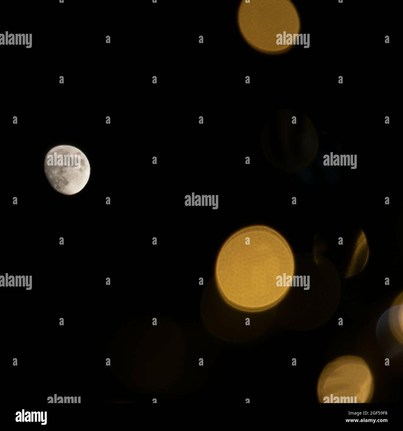 Waxing gibbous moon against a night sky with scattered bokeh lights