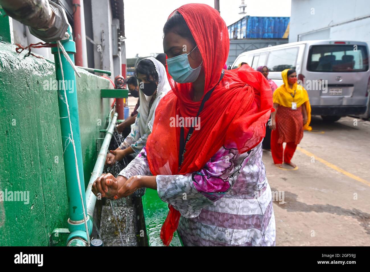 Dhaka. 23rd Aug, 2021. Workers wash their hands before entering a