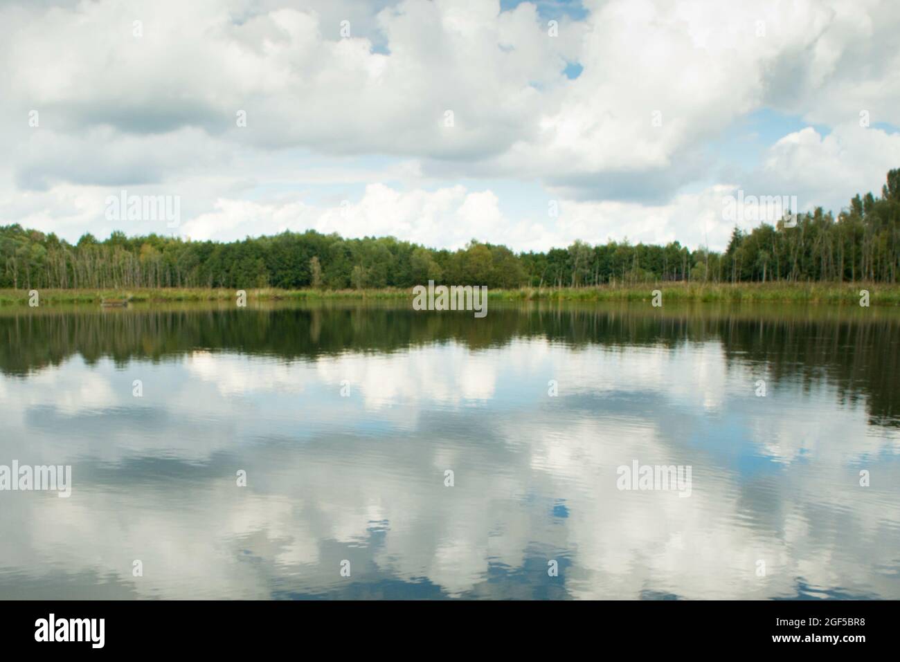 Scenic view of a wide lake surrounded by lush forests on a cloudy sky ...