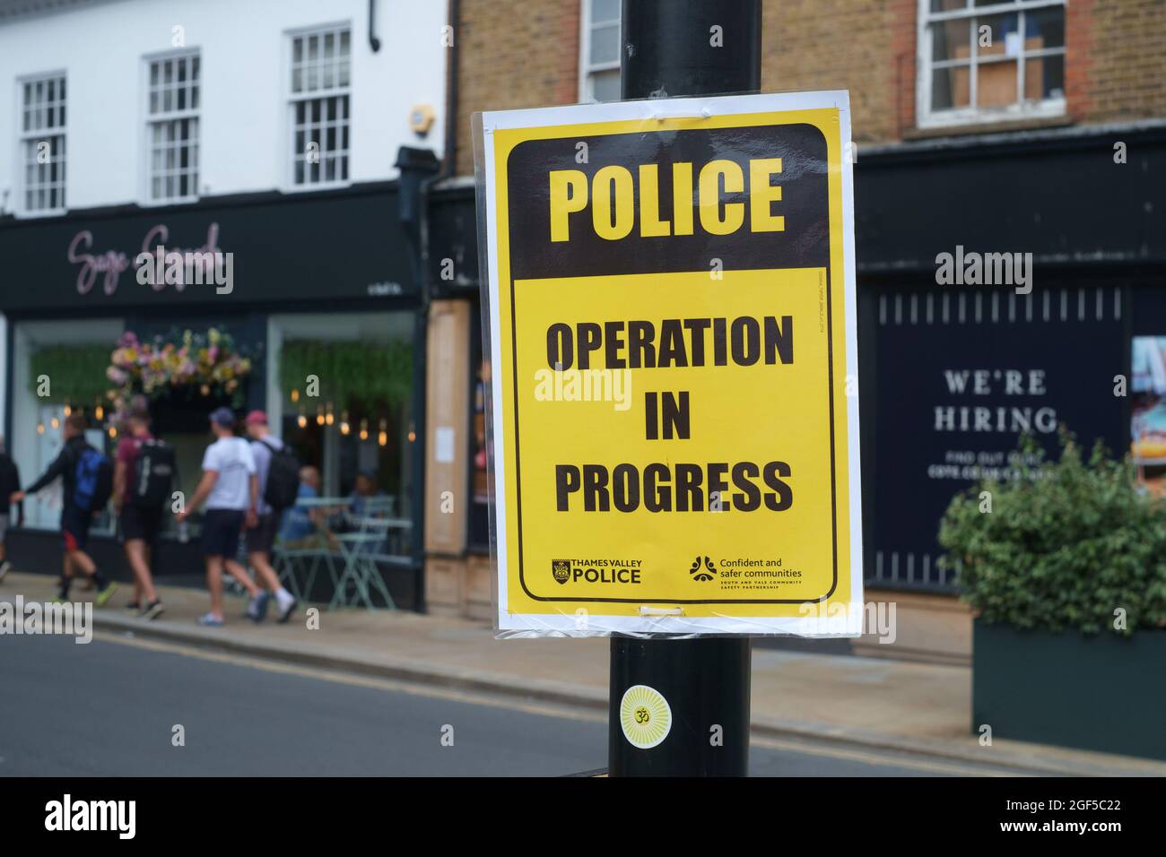 A yellow  'Police Operation in Progress' sign attached to a lamp post from Thames Valley Police Stock Photo