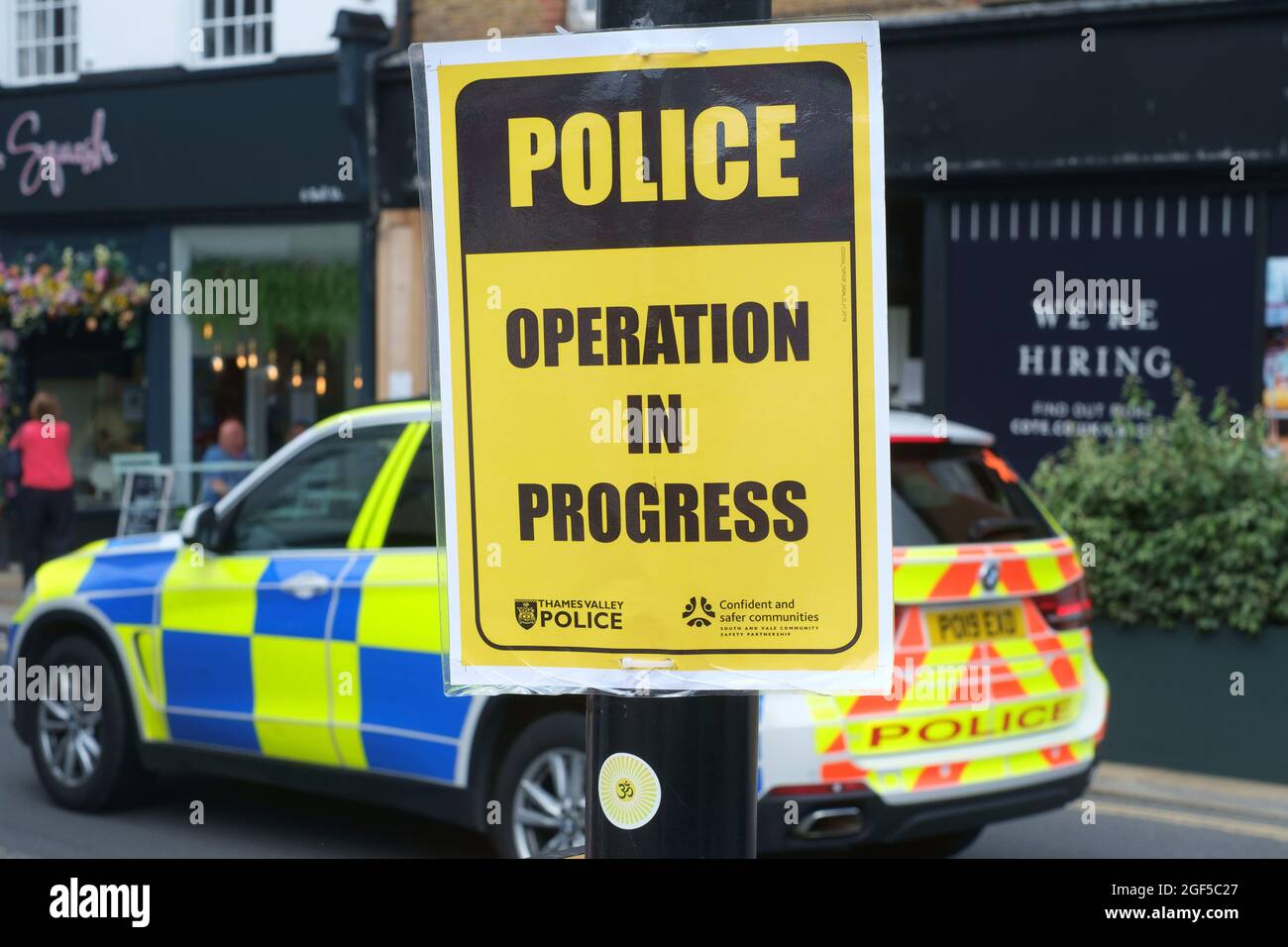 A yellow  'Police Operation in Progress' sign attached to a lamp post from Thames Valley Police Stock Photo