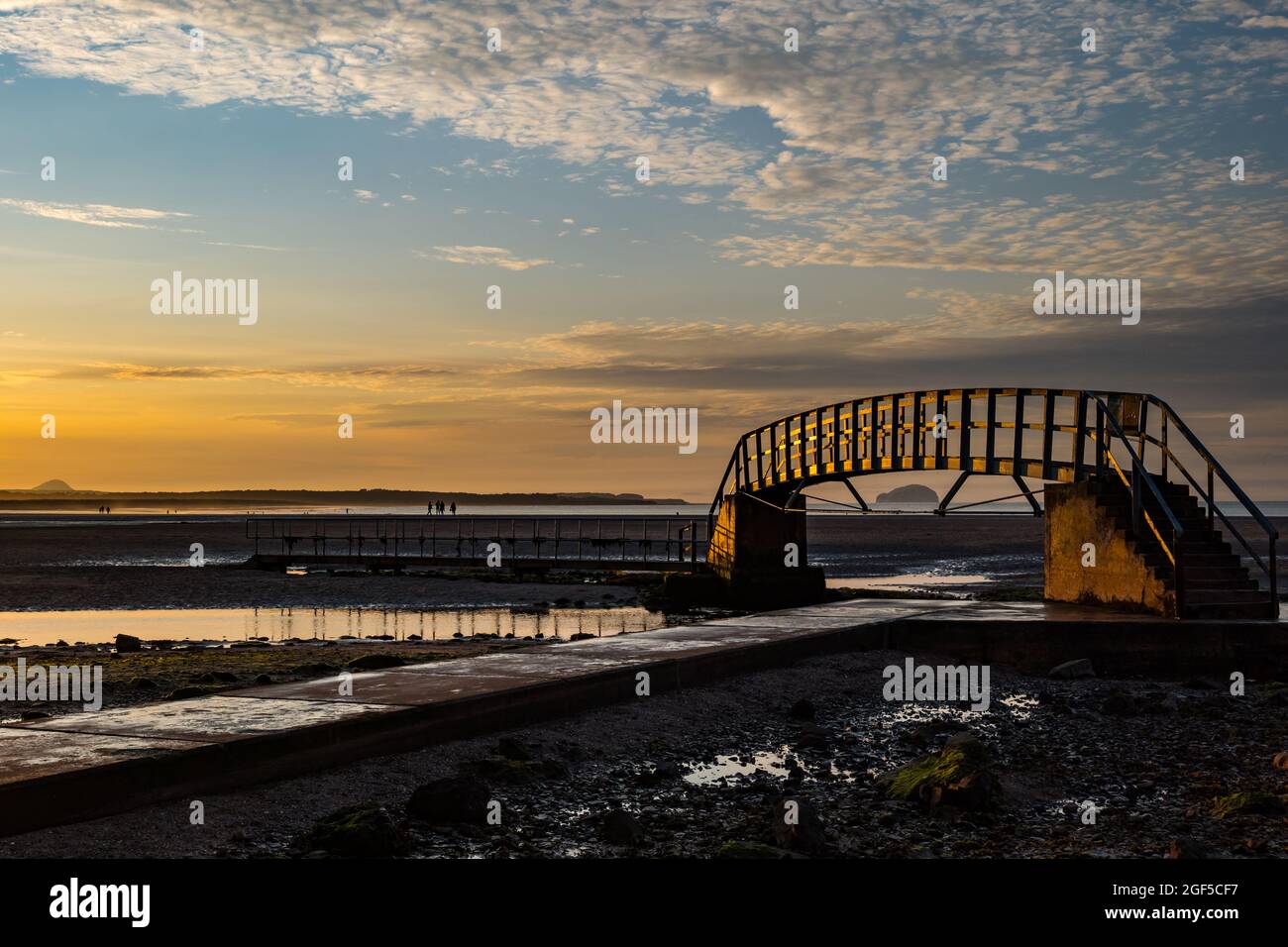 Dunbar, East Lothian, Scotland, United Kingdom, 23rd August 2021. UK Weather: sunset at Belhaven Bay. A warm evening with a colourful sky as the sun sets at low tide with the so-called 'Bridge to Nowhere' footbridge Stock Photo