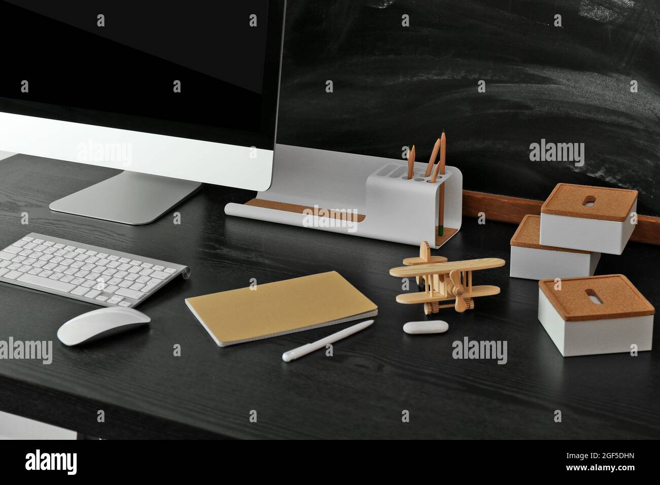 Desktop with computer monitor and other items against blackboard