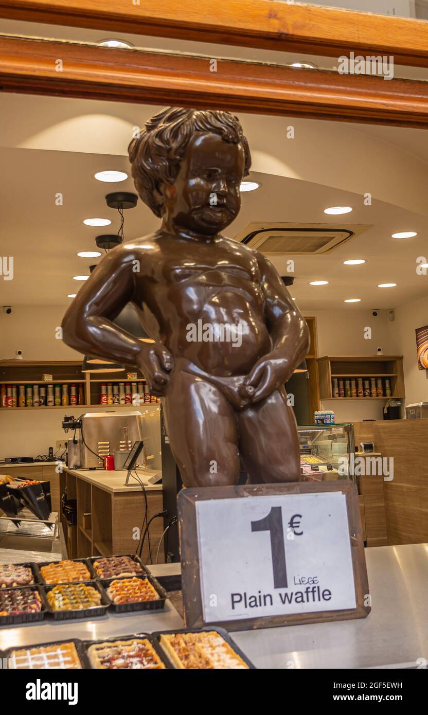 Brussels, Belgium - July 31, 2021: Closeup of giant chocolate Manneken Pis statue at open window of shop selling waffles and chocolates. Stock Photo