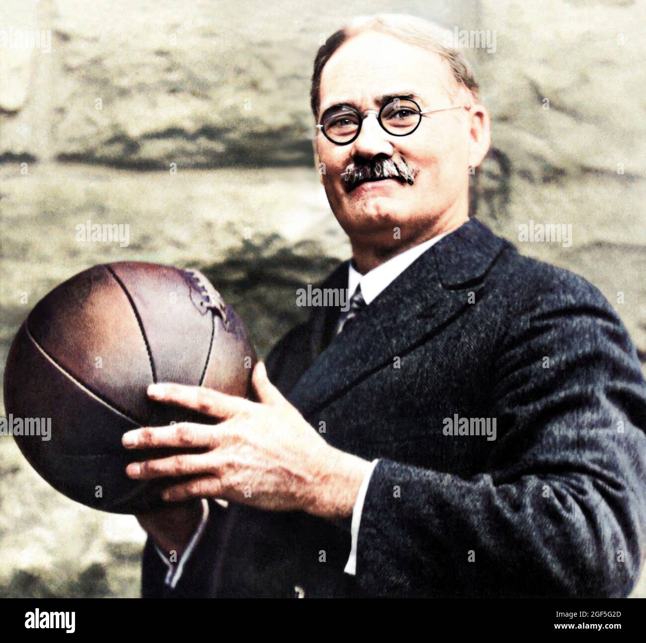 1930 ca , USA : The american Doctor JAMES A. NAISMITH ( 1861 - 1939 ), born-canadian, inventor of BASKETBALL sport . he wrote the original basketball rule book and founded the University of Kansas basketballs program . Unknown photographer . DIGITALLY COLORIZED . - BASKET - JIM THE DOC - SPORT  -  PALLACANESTRO - INVENTORE - INVENZIONE - INVENTION - DISCIPLINA SPORTIVA - Dottore - HISTORY - FOTO STORICHE - PORTRAIT - RITRATTO - prato - grass - meadow - palla - ball - cravatta - tie - occhiali da vista - lens ----  Archivio GBB Stock Photo