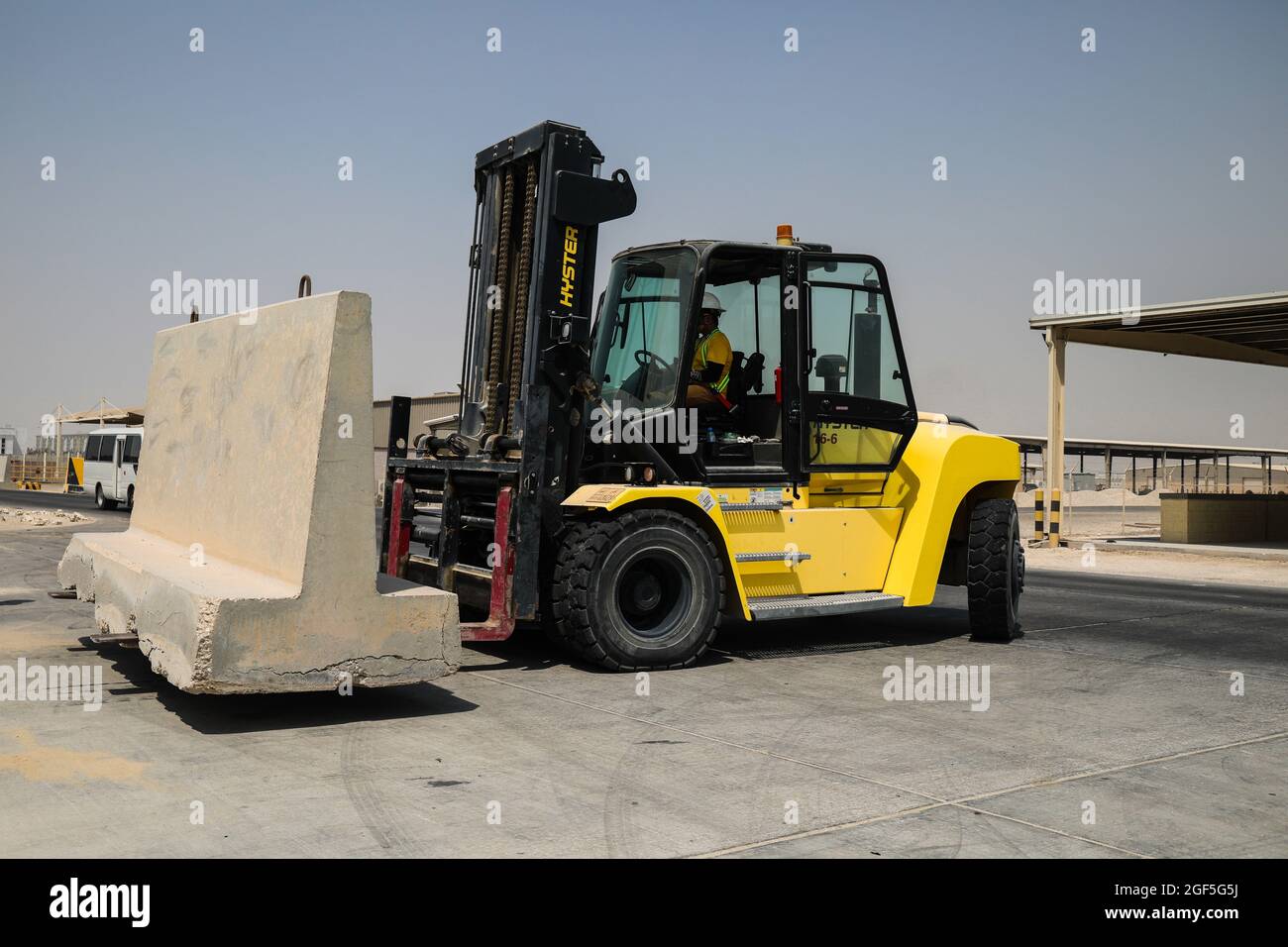 A civilian contractor operates a forklift to move a concrete T-Wall to provide additional security for Afghan evacuees in the CENTCOM AOR, Aug. 22, 2021. U.S. service members are assisting the Department of State with an orderly drawdown of designated personnel in Afghanistan. (U.S. Army photo by Sgt. Jimmie Baker) Stock Photo