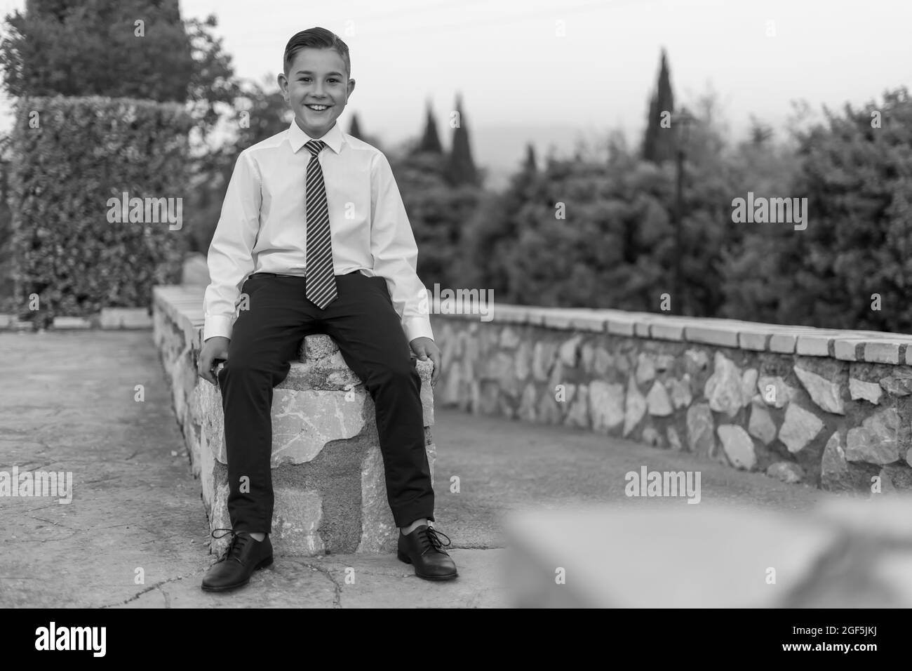 Grayscale shot of an adorable male child in a formal suit outfit posing Stock Photo