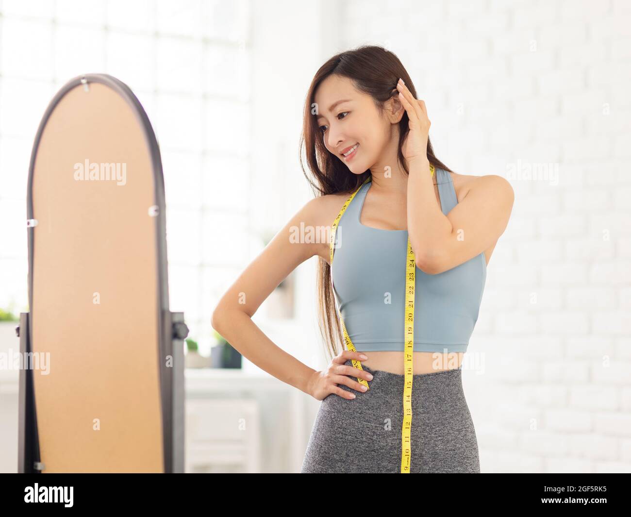 Young woman with tape standing in front of mirror.Weight Loss. Stock Photo