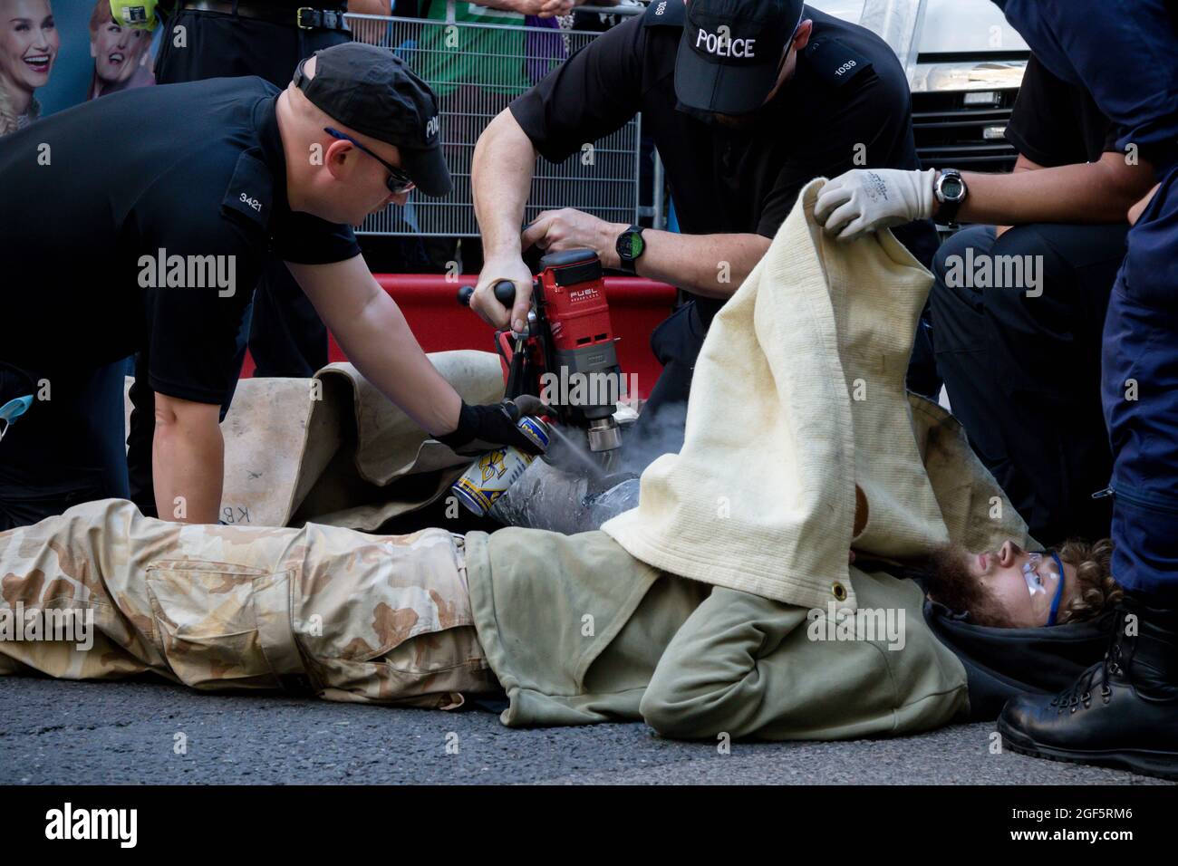 London, United Kingdom, 21st August 2021:- Specialist police officers use cutting equipment to remove Extinction Rebellion protesters from a metal pip Stock Photo