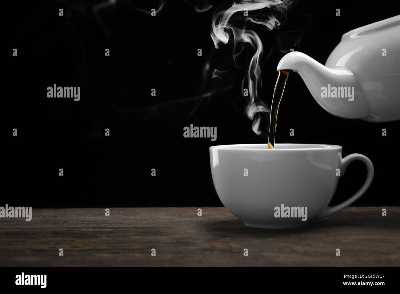 Pouring hot tea from a kettle into a cup on black background, close up Stock Photo Alamy