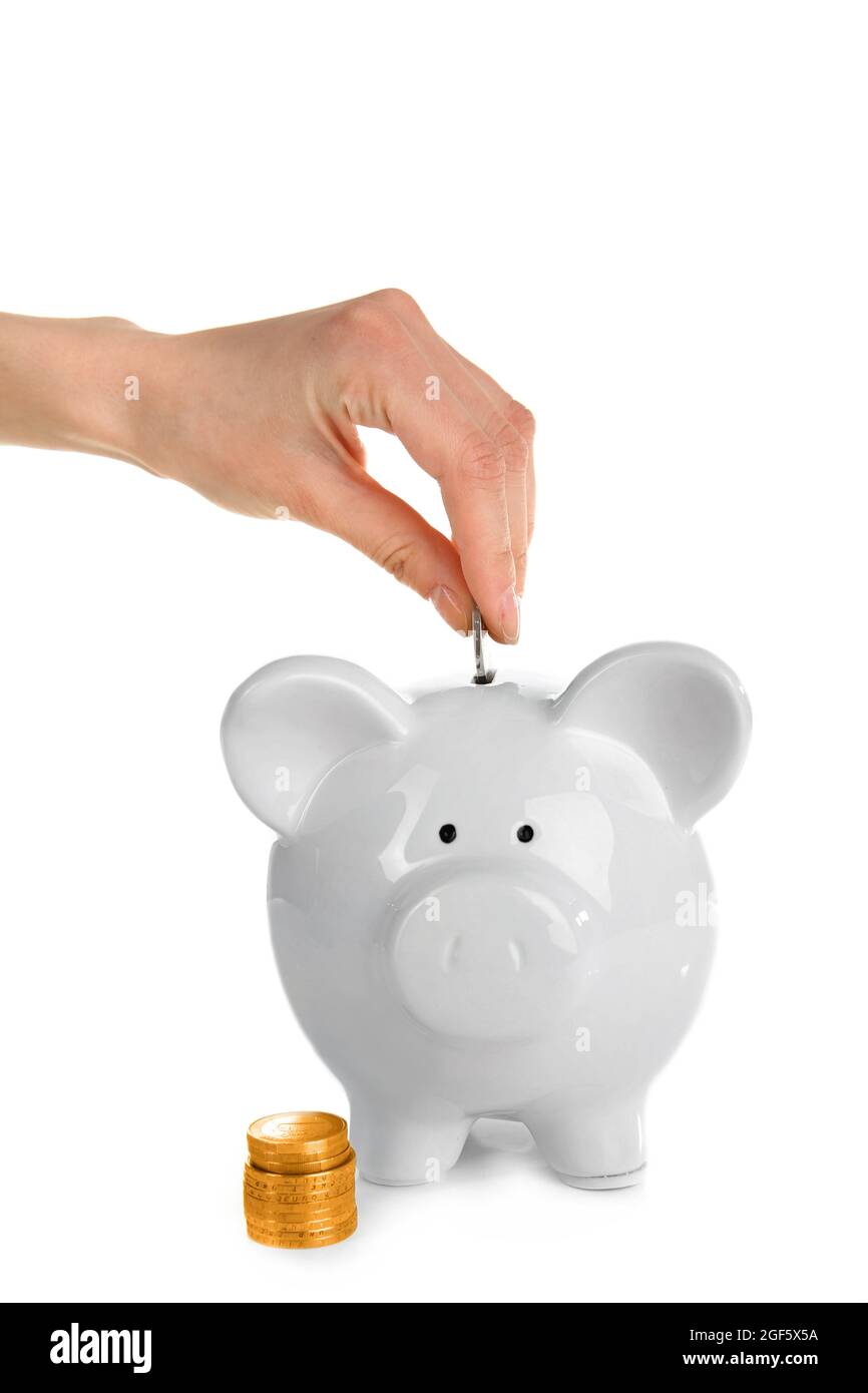 Hand putting coin into piggy bank, isolated on white Stock Photo - Alamy