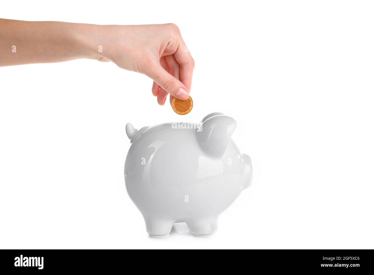 Hand putting coin into piggy bank, isolated on white Stock Photo - Alamy