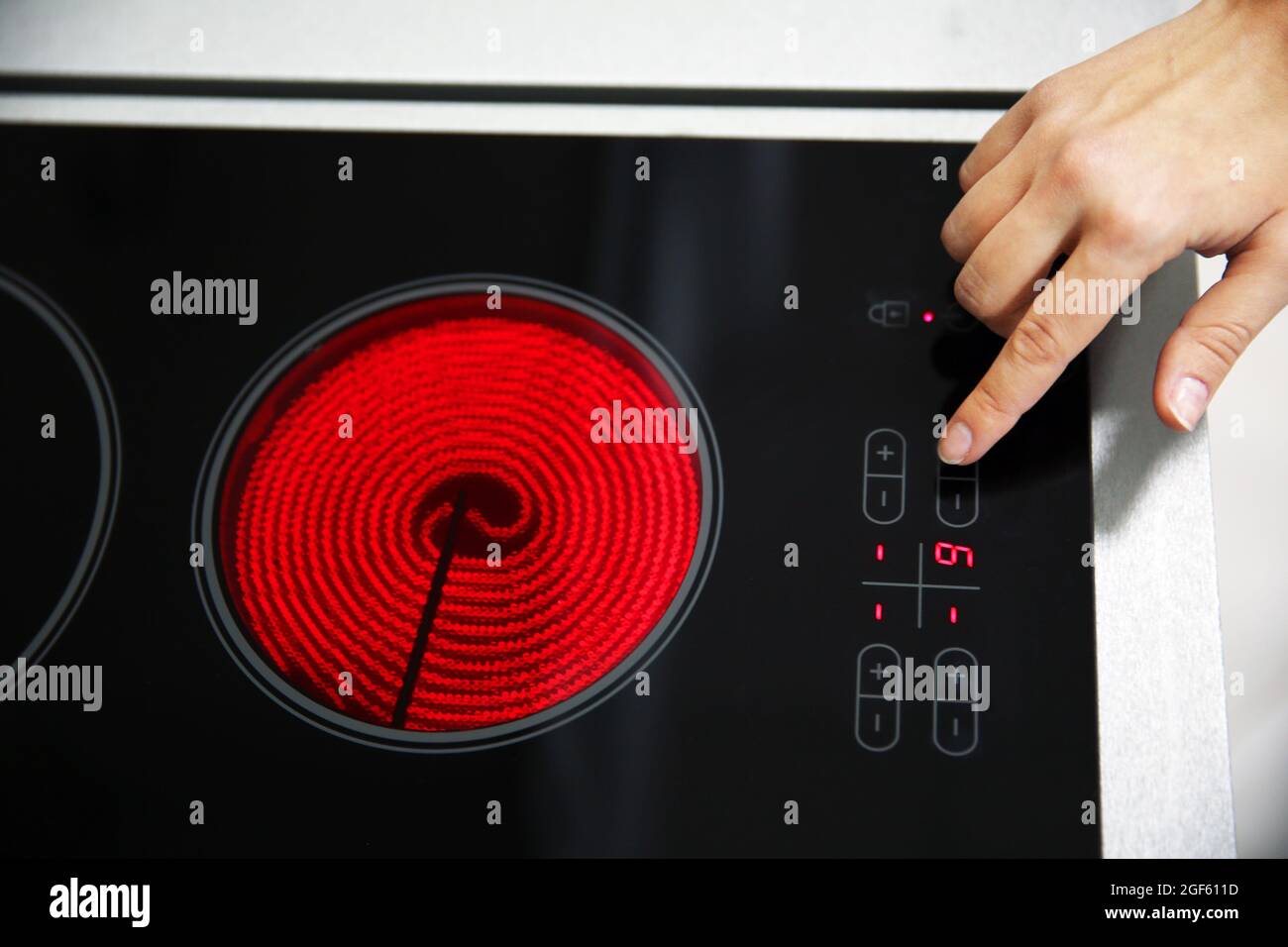 Female hand turns on electric hob closeup Stock Photo Alamy