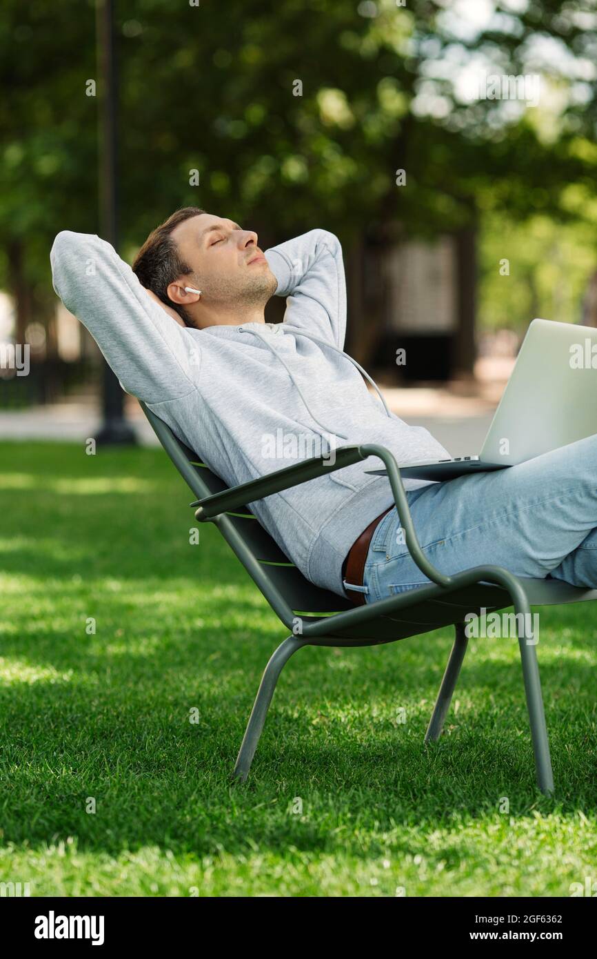 Freelancer blogger man with laptop rest after work outdoors, listens music take a break. Nap concept Stock Photo