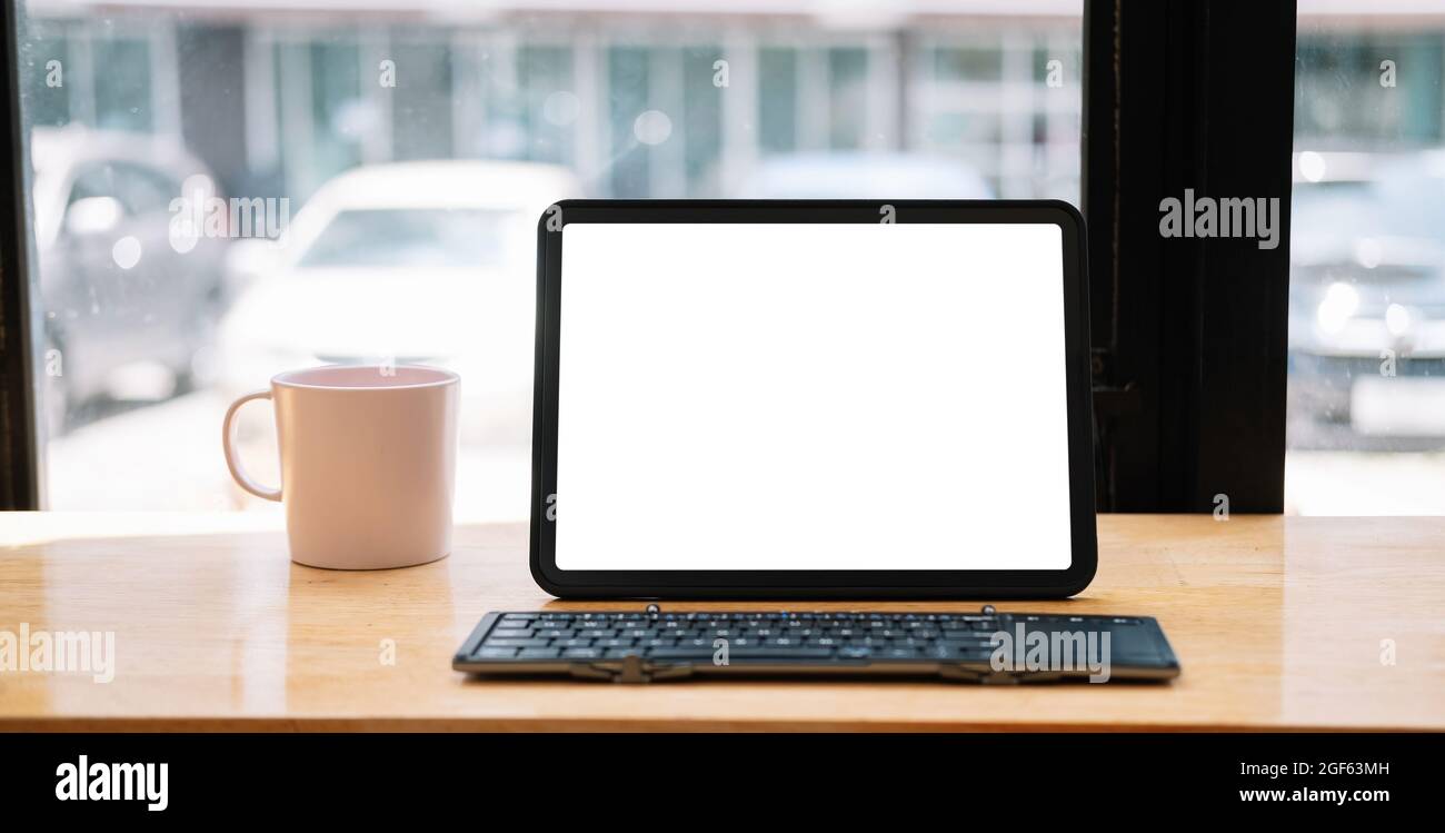 Shot of digital tablet with blank white screen, keyboard, cup of coffee on workspace desk Stock Photo