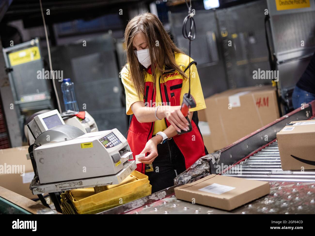 19 August 2021, Baden-Wuerttemberg, Köngen: Adriana Tec, dispatcher at the  DHL parcel centre in Köngen, scans barcodes on parcels during her night  shift. (to dpa: "High parcel volume at DHL distribution centre -
