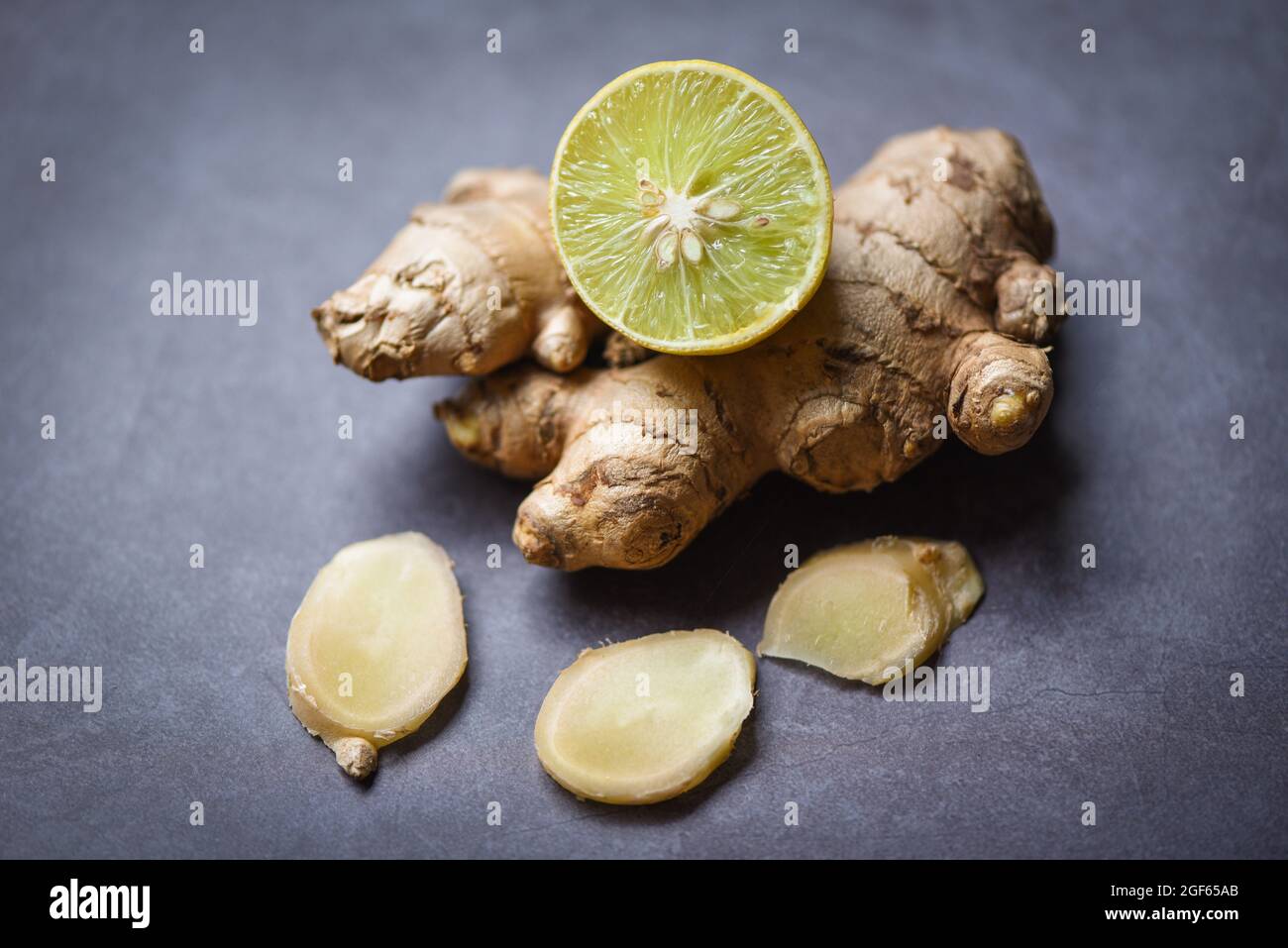 Fresh ginger root on dark background with sliced ginger and lemon lime Stock Photo