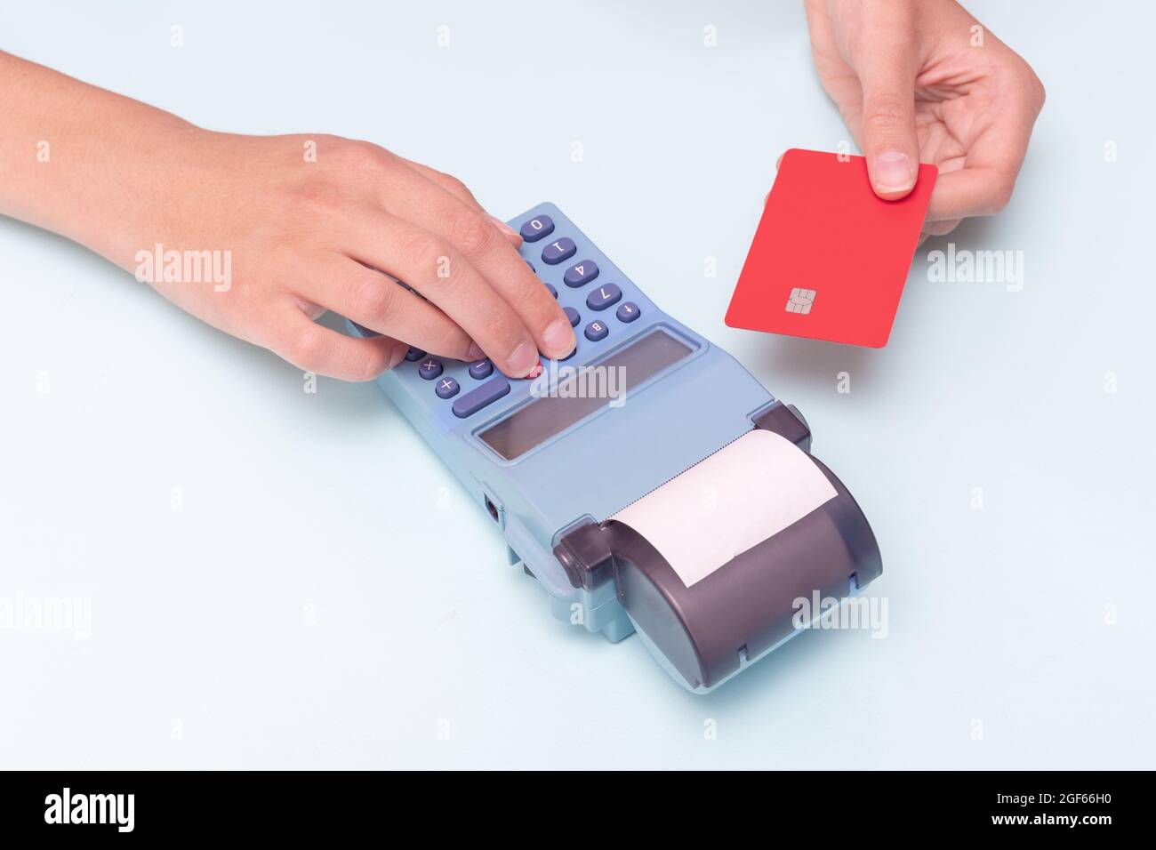 Payment for purchases by credit card. Close-up of a hand holding a bank card and a hand holding a check, receipt on a cash register on a blue backgrou Stock Photo