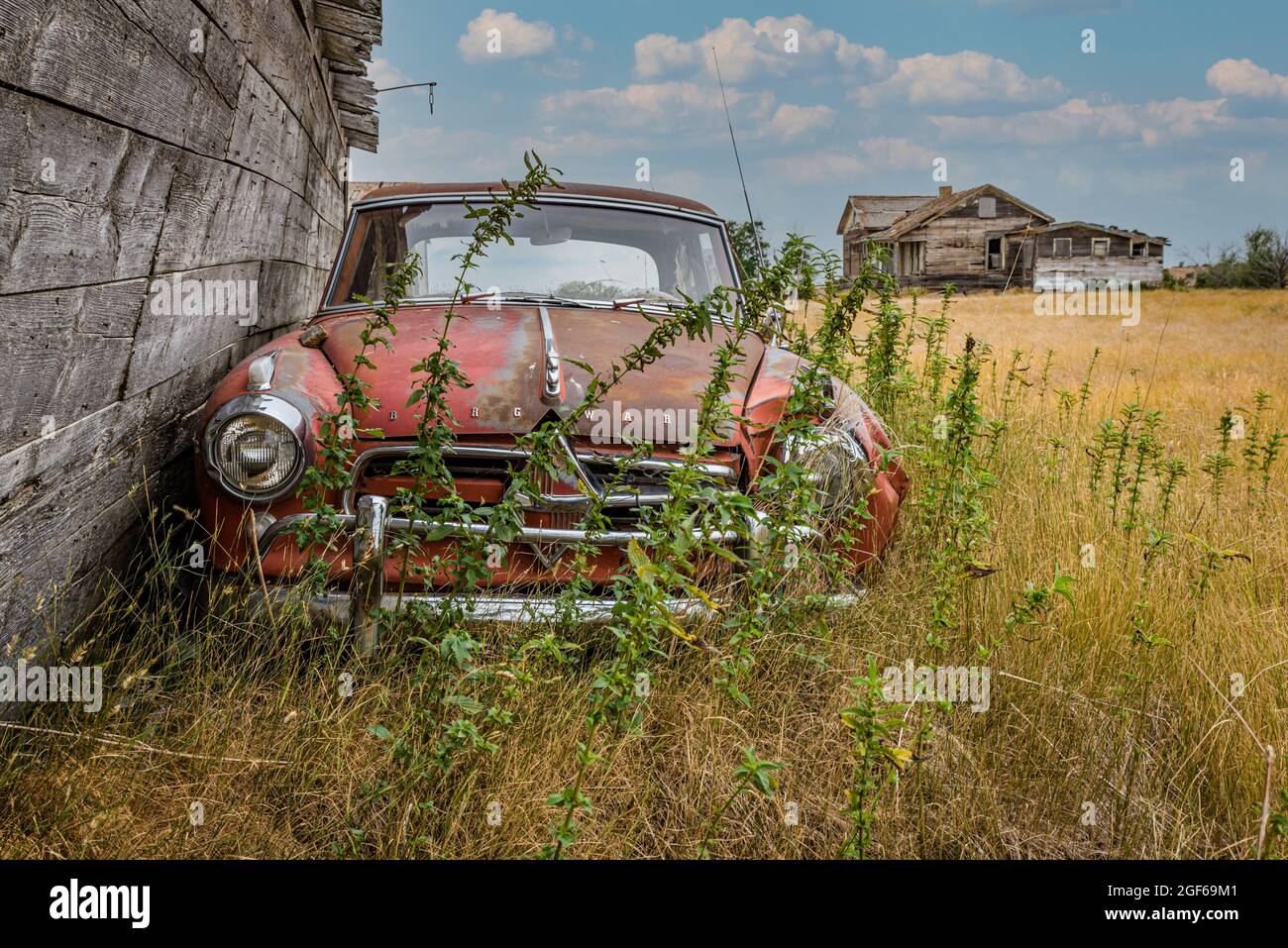 Rush Lake, SK- August 19, 2021: An abandoned Borgward Isabella TS classic coupe and abandoned farmhouse on the Saskatchewan prairies Stock Photo
