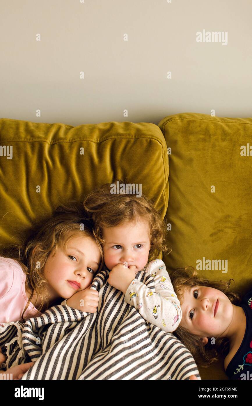 Cute little girls chilling on soft couch in living room together at home Stock Photo