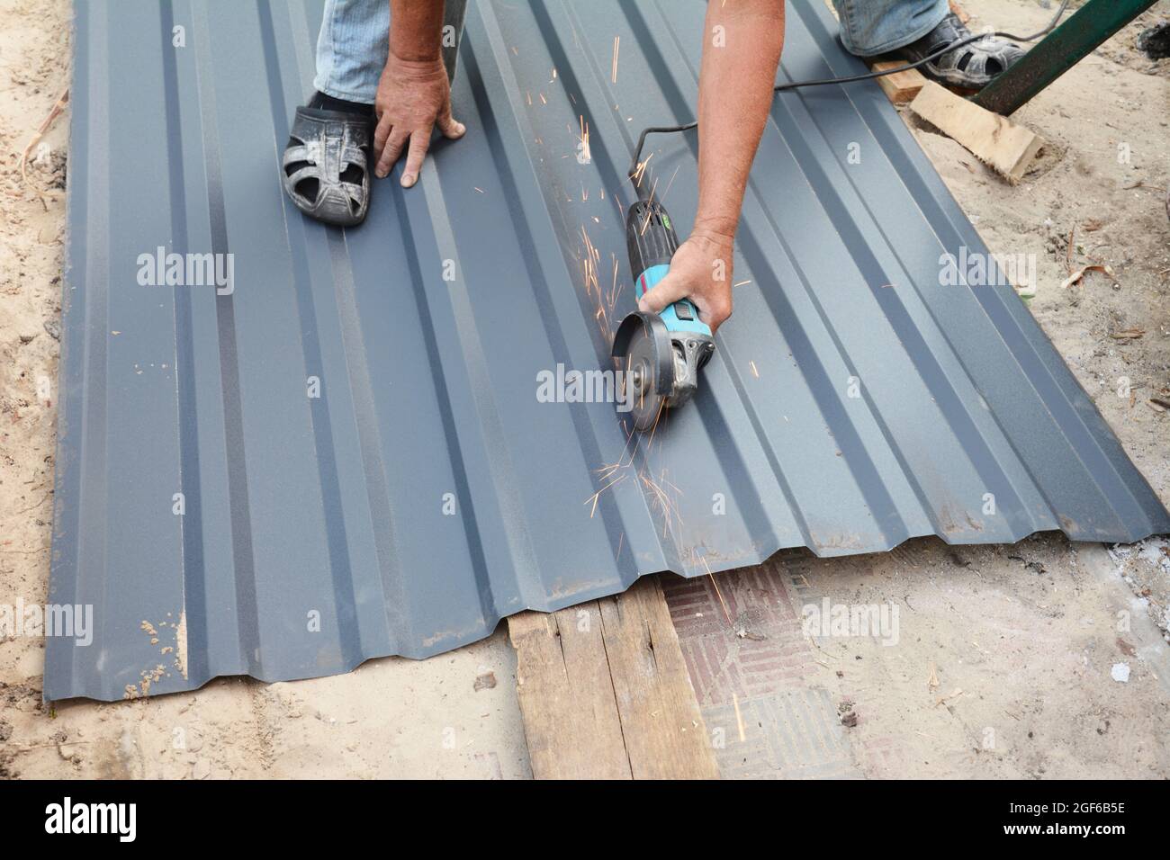 A building contractor is cutting corrugated metal roof sheet using an