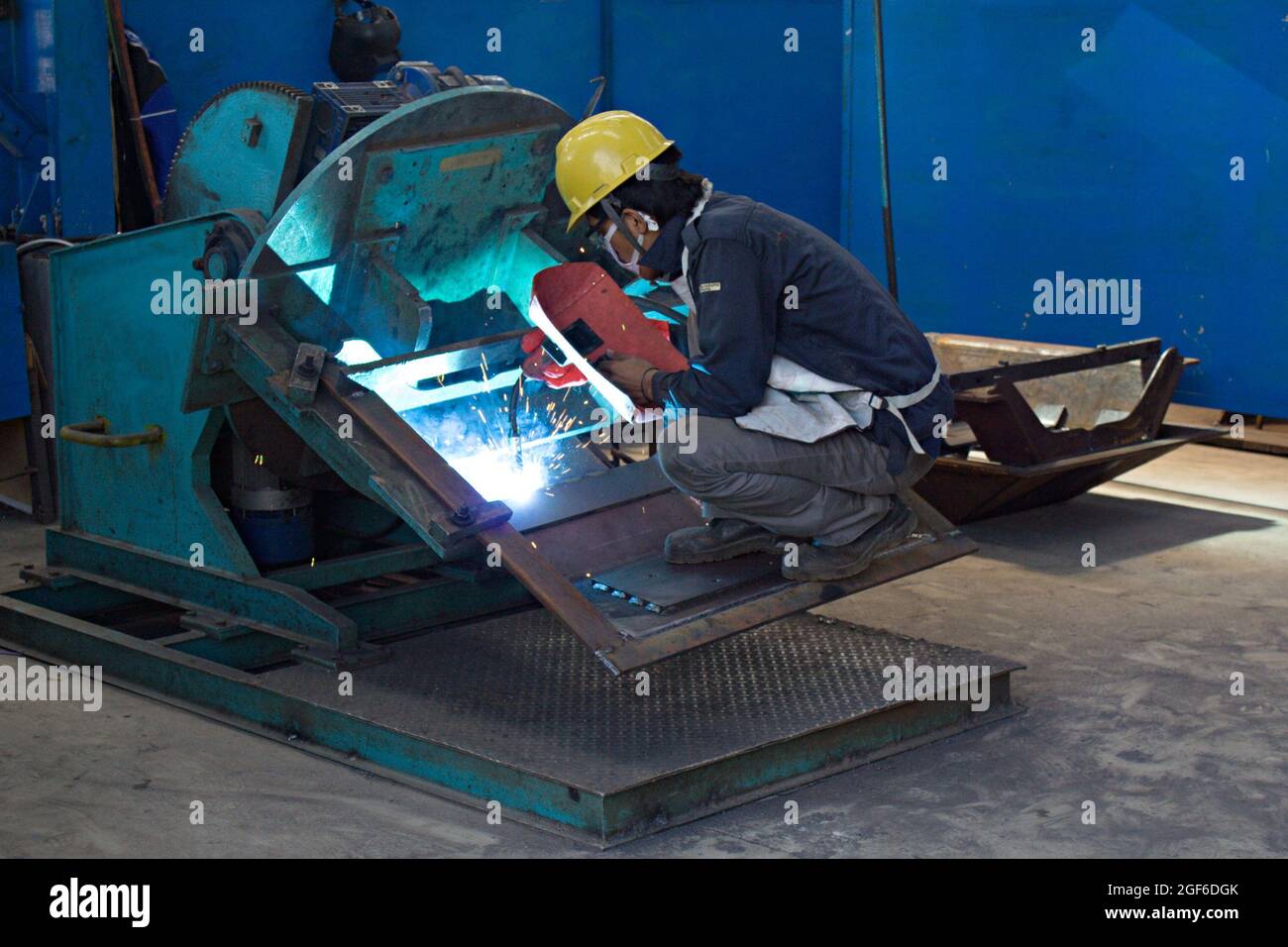 A welder is using an electric arc welding machine in a fabrication workshop. Stock Photo