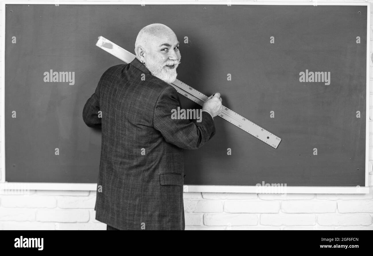 line drawing. geometric shapes at high school. senior man teacher use ruler while drawing. bearded tutor man draw with ruler on blackboard. back to Stock Photo