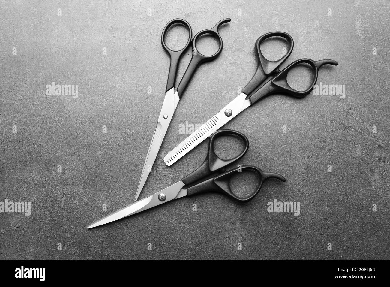Professional metal scissors lying close to each other on a dark grey