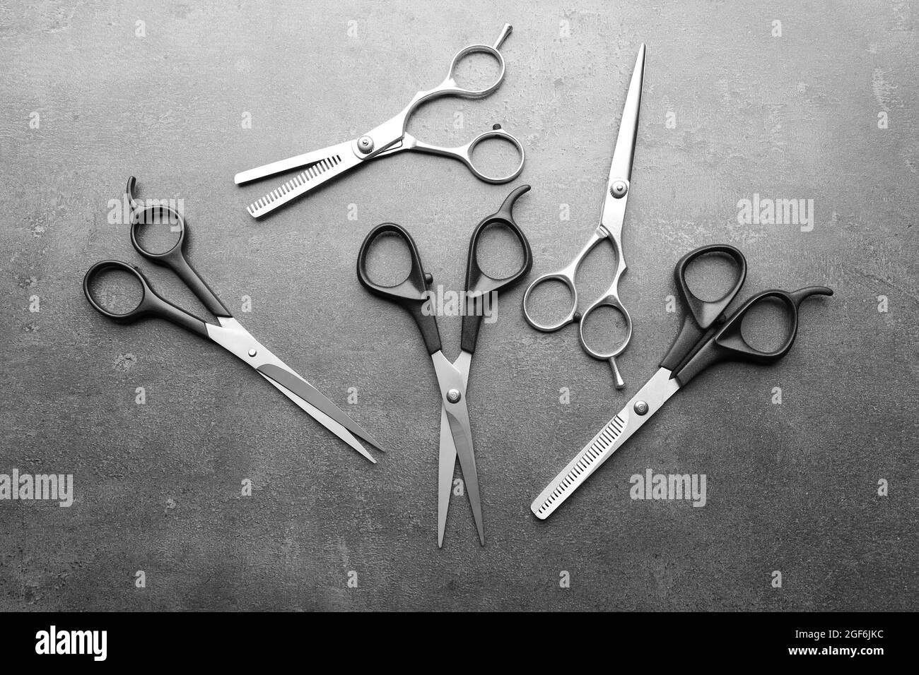 Professional metal scissors laying chaotically on a dark grey surface ...