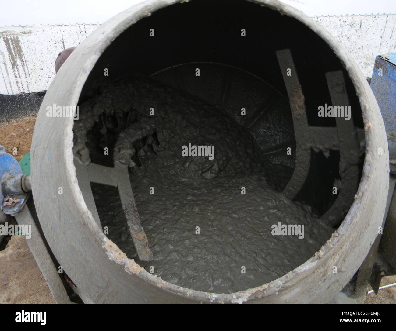 A closeup of a cement mixer machine, barrel type mixer mixing concrete
