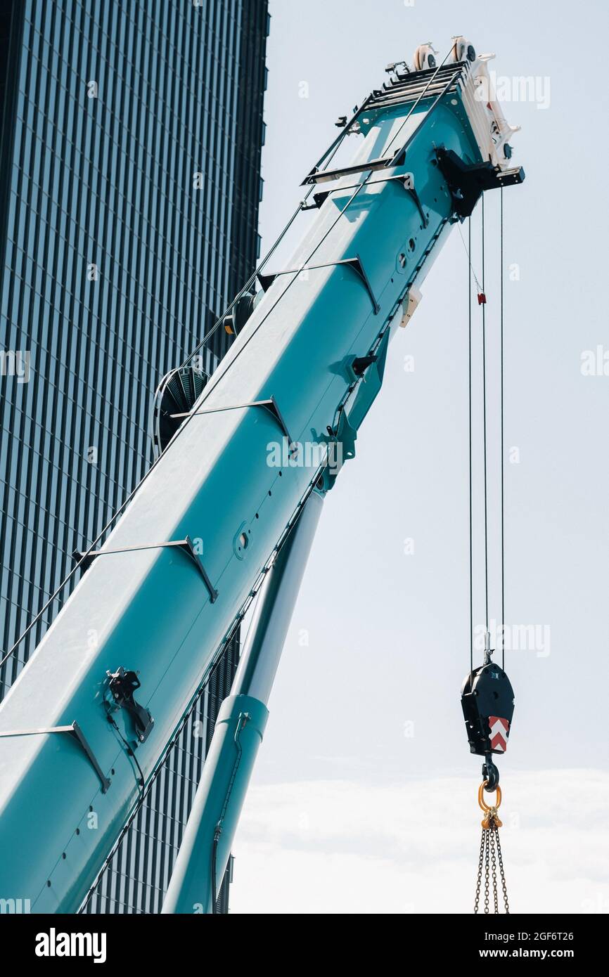 blue crane lifting mechanism with hooks near the glass modern building