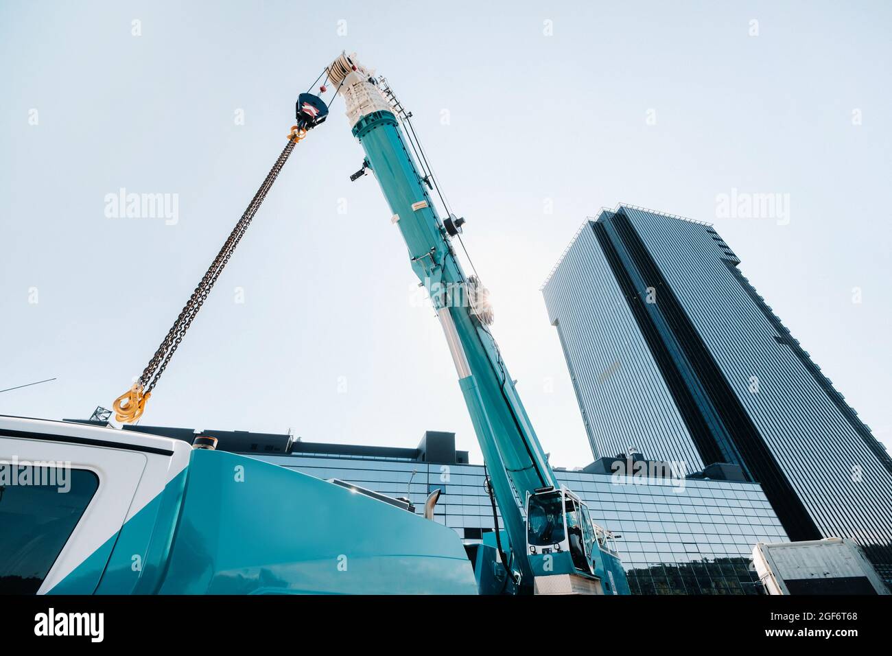 blue crane lifting mechanism with hooks near the glass modern building