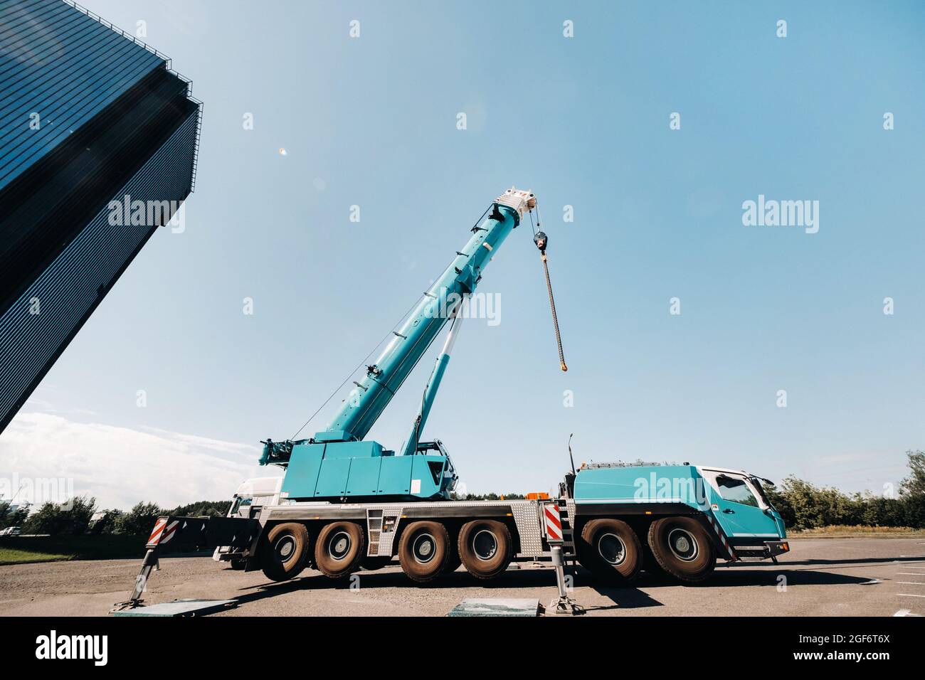 blue crane lifting mechanism with hooks near the glass modern building